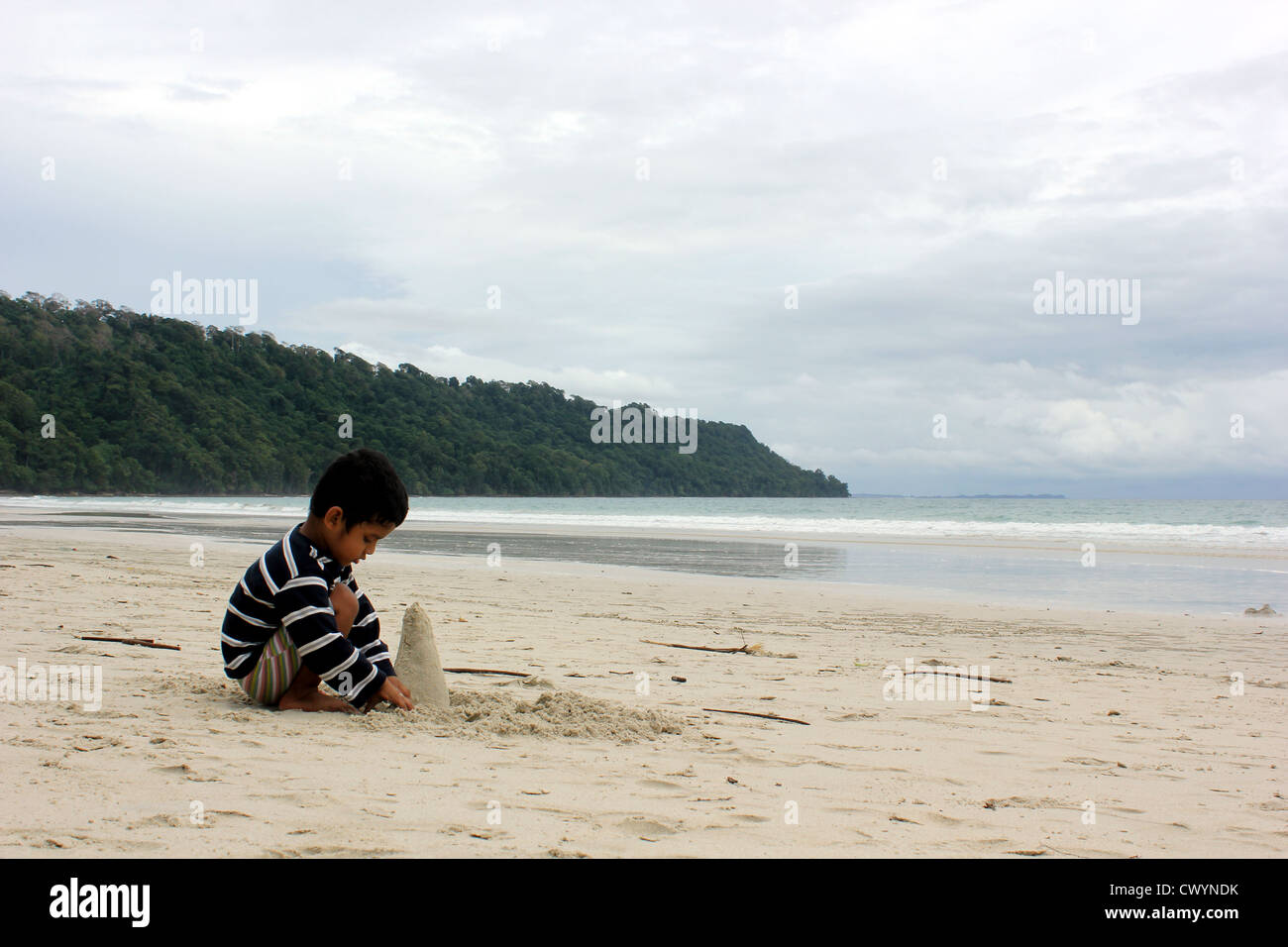 Niño jugando con la arena en la playa Radha Nagar, Havelock Island, Islas de Andaman. Foto de stock