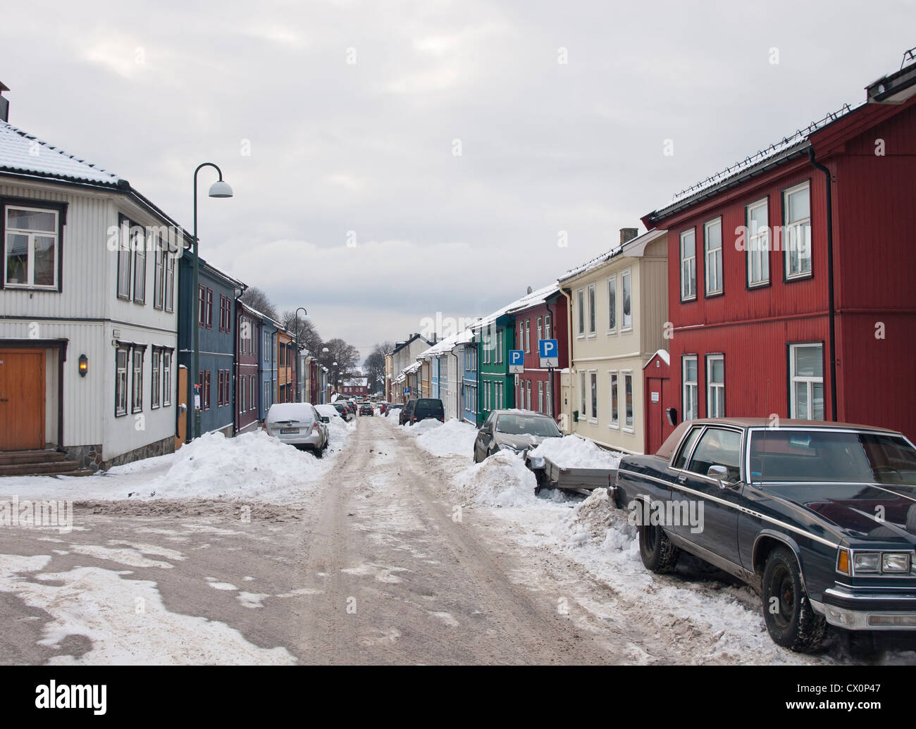 Invierno en Oslo, Noruega, una calle de Vålerenga con antiguas casas de madera, la nieve no eliminados y los problemas de aparcamiento para el residente Foto de stock