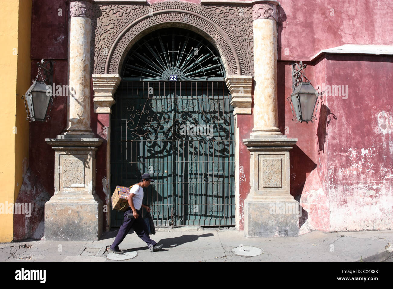 Hombre caminando local pasado ornamentada portada en el Patrimonio Mundial de la UNESCO [Sitio] de Antigua, Guatemala, América Central Foto de stock