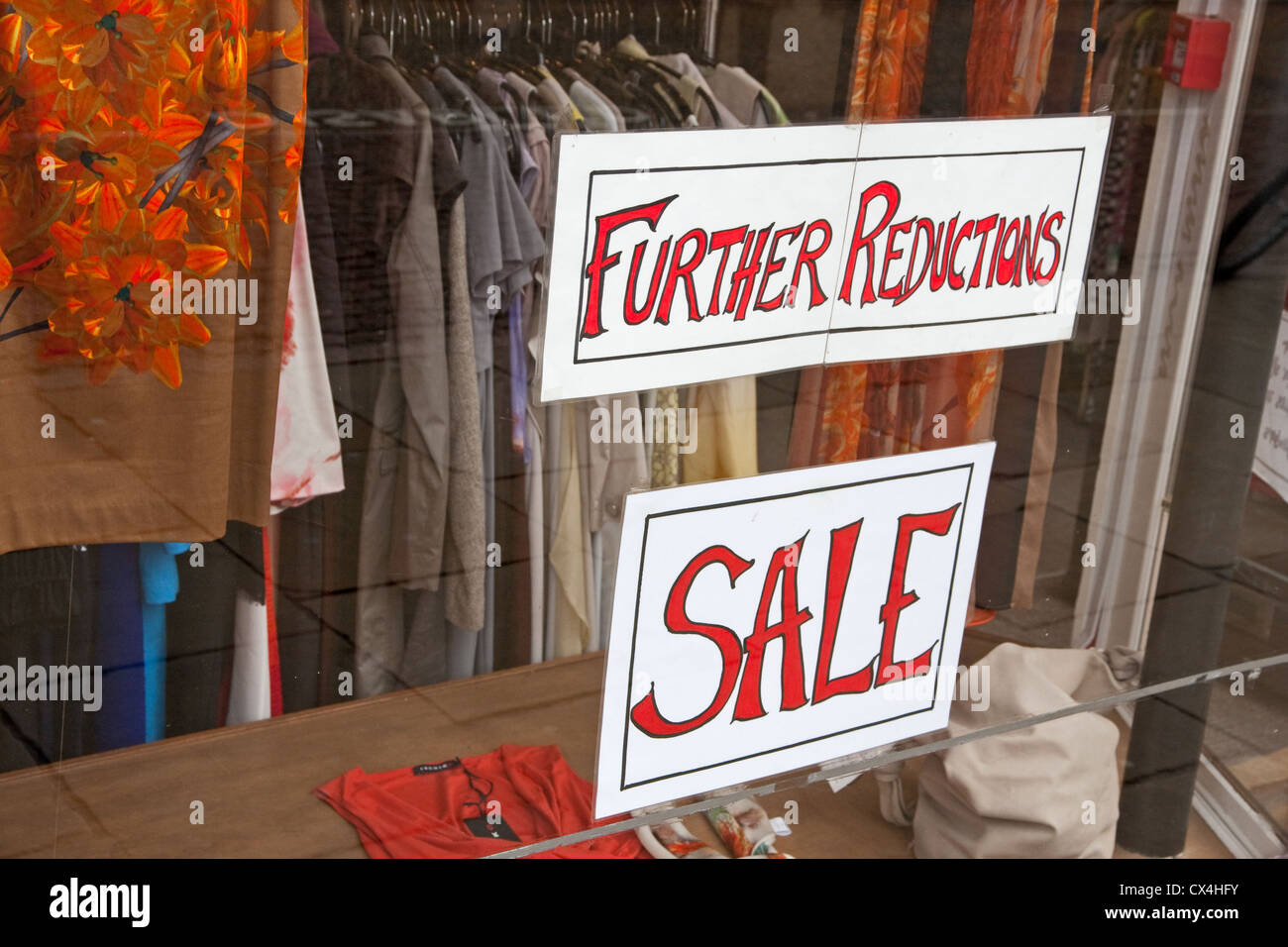 Nuevas reducciones, la venta de avisos en ventana de la tienda de ropa. Foto de stock