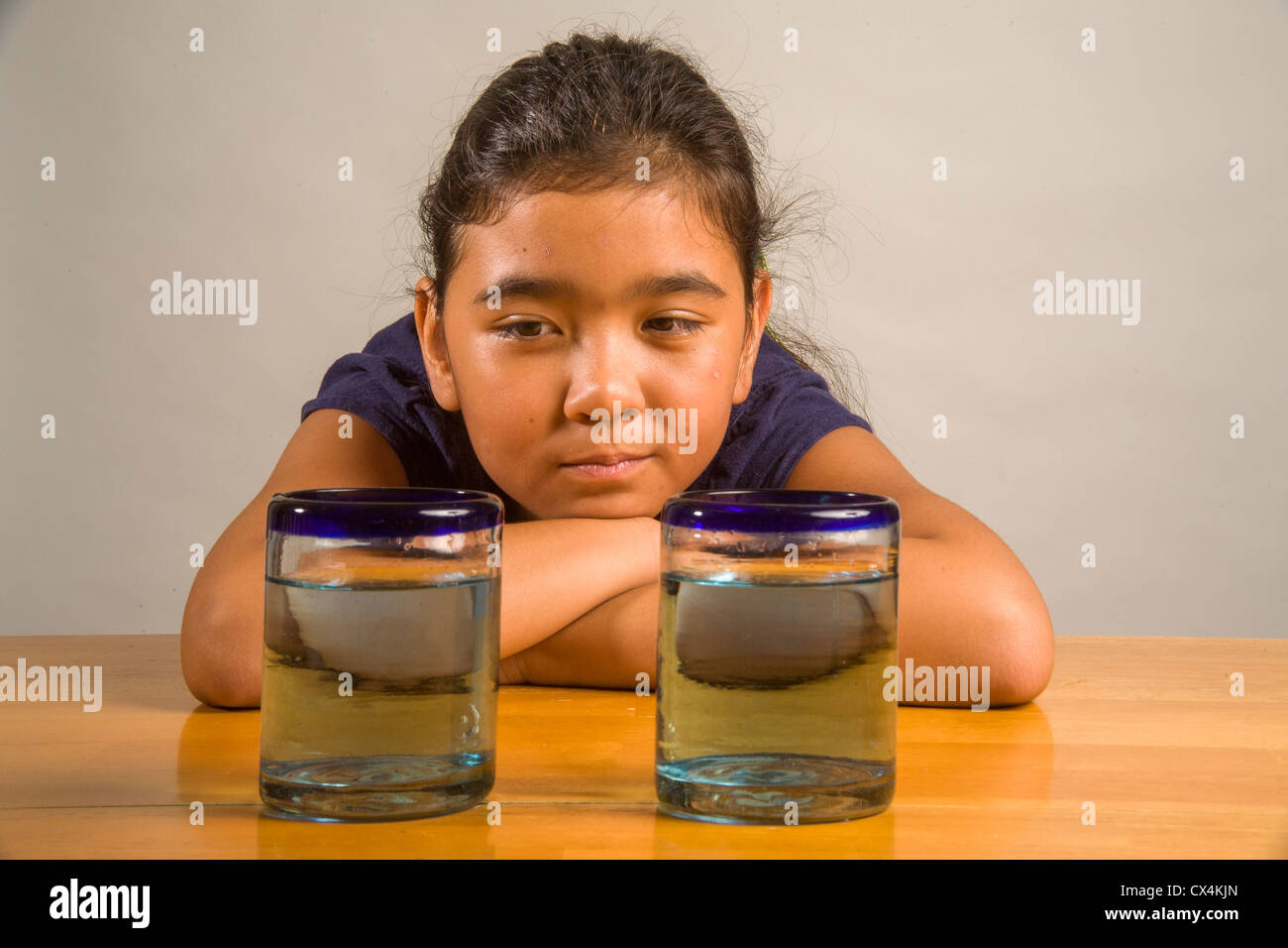Un niño mira idénticos vasos llenos de la misma cantidad de líquido