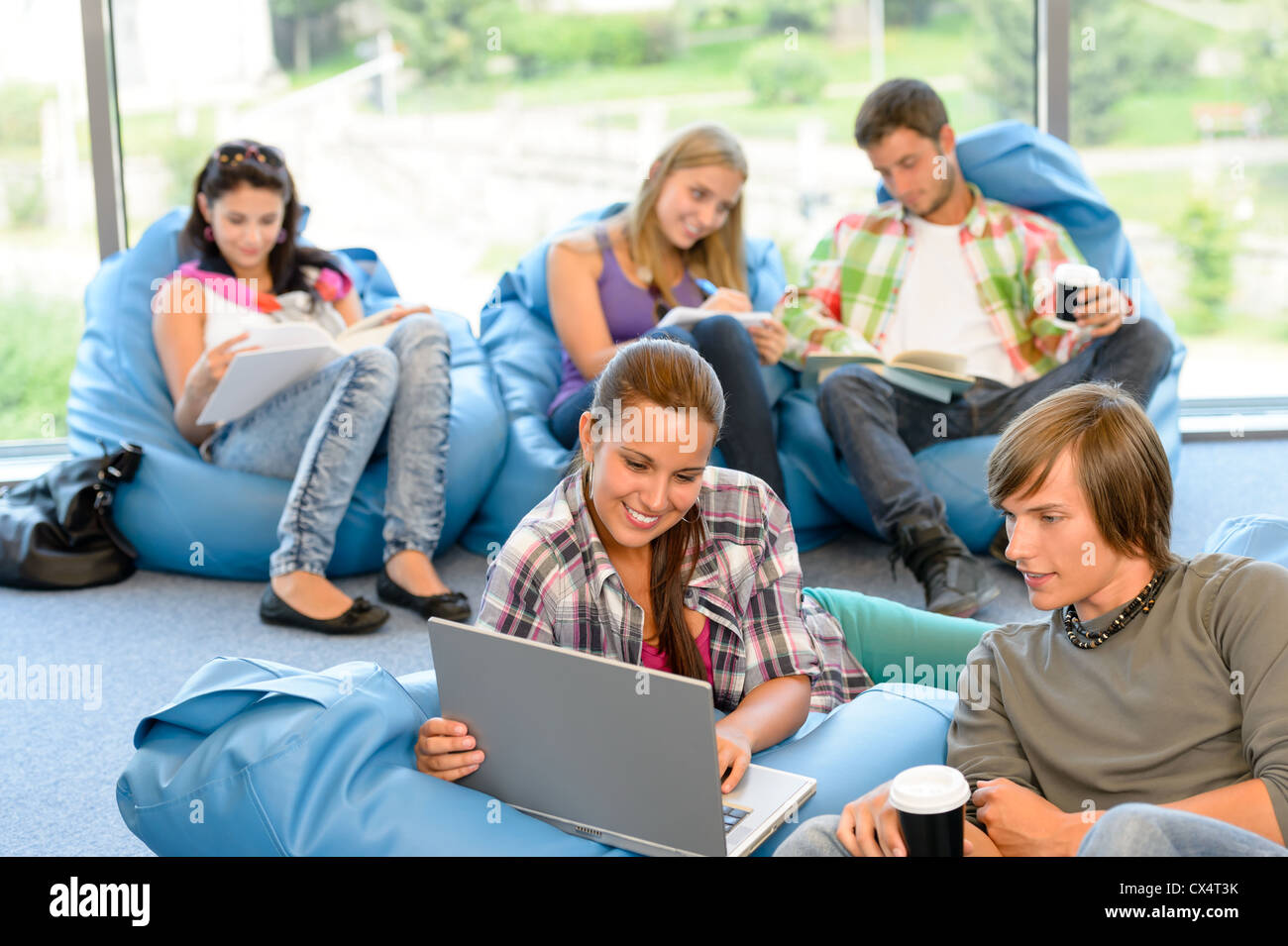 Estudiantes sentados en bolsas de semillas sala de estudio feliz adolescentes de secundaria Foto de stock