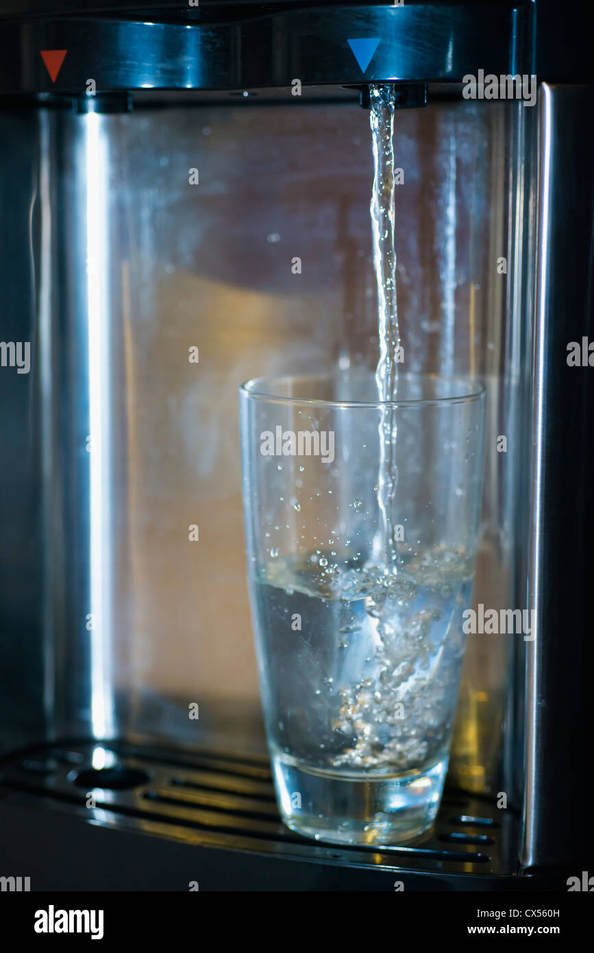 Dispensador De Agua Mujer Tomando Agua Fría En El Vidrio De La