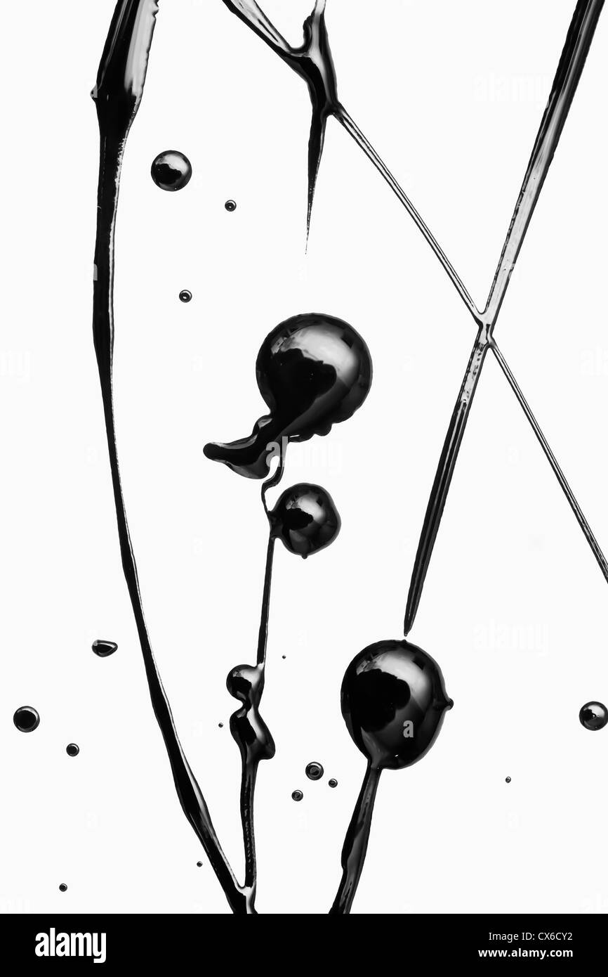 Salpicado de pintura negra sobre una superficie blanca haciendo un elegante patrón Foto de stock