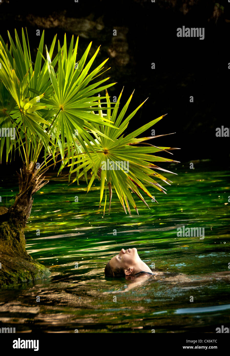 Mujer disfrutando del agua debajo de un ventilador palma de la Chac Mool  Centote en uno de los sistemas de cavernas de la Riviera Maya, México  Fotografía de stock - Alamy