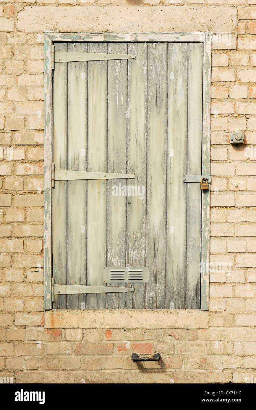 Peeling de puerta de madera en una vieja pared de ladrillos Foto de stock