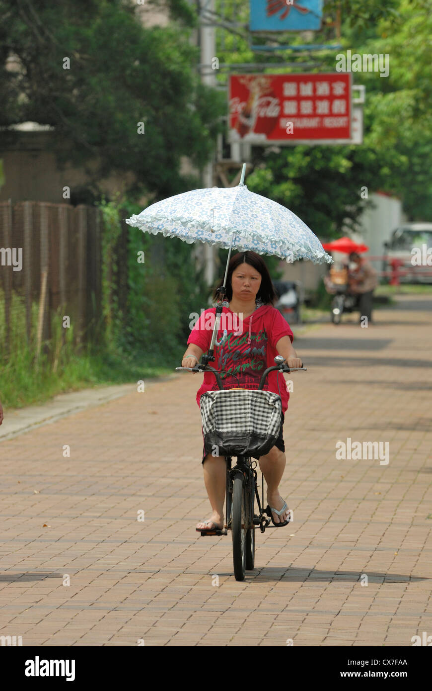 Mujer asiática con sombrilla a montar una bicicleta en la calle de Mui Wo  China Fotografía de stock - Alamy