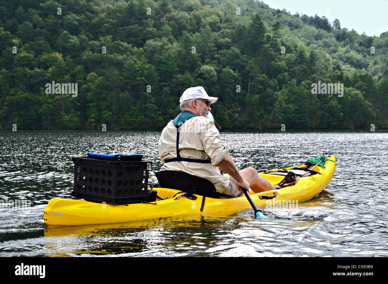 Un hombre de edad avanzada en un kayak en un tranquilo lago en la montaña. Foto de stock