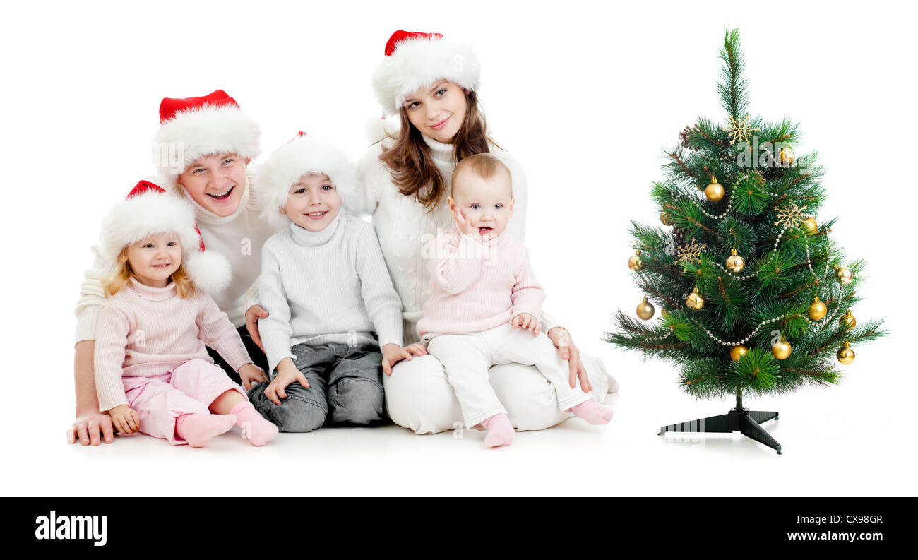 Familia feliz en sombreros de Snta cerca del árbol de navidad aislado en blanco Foto de stock