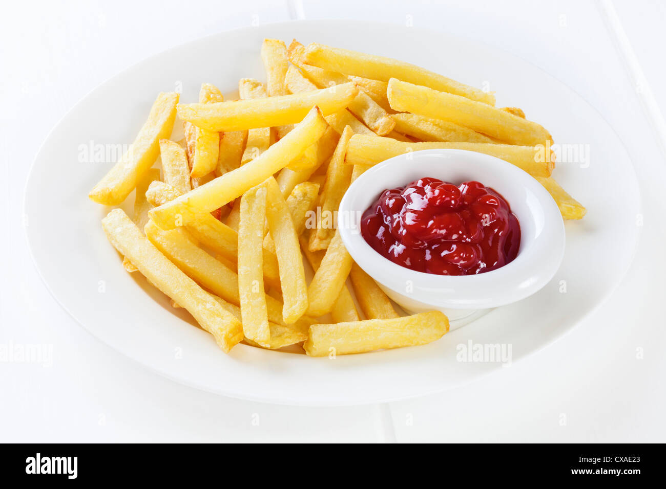 Un plato de papas fritas con ketchup en un pequeño recipiente. Foto de stock