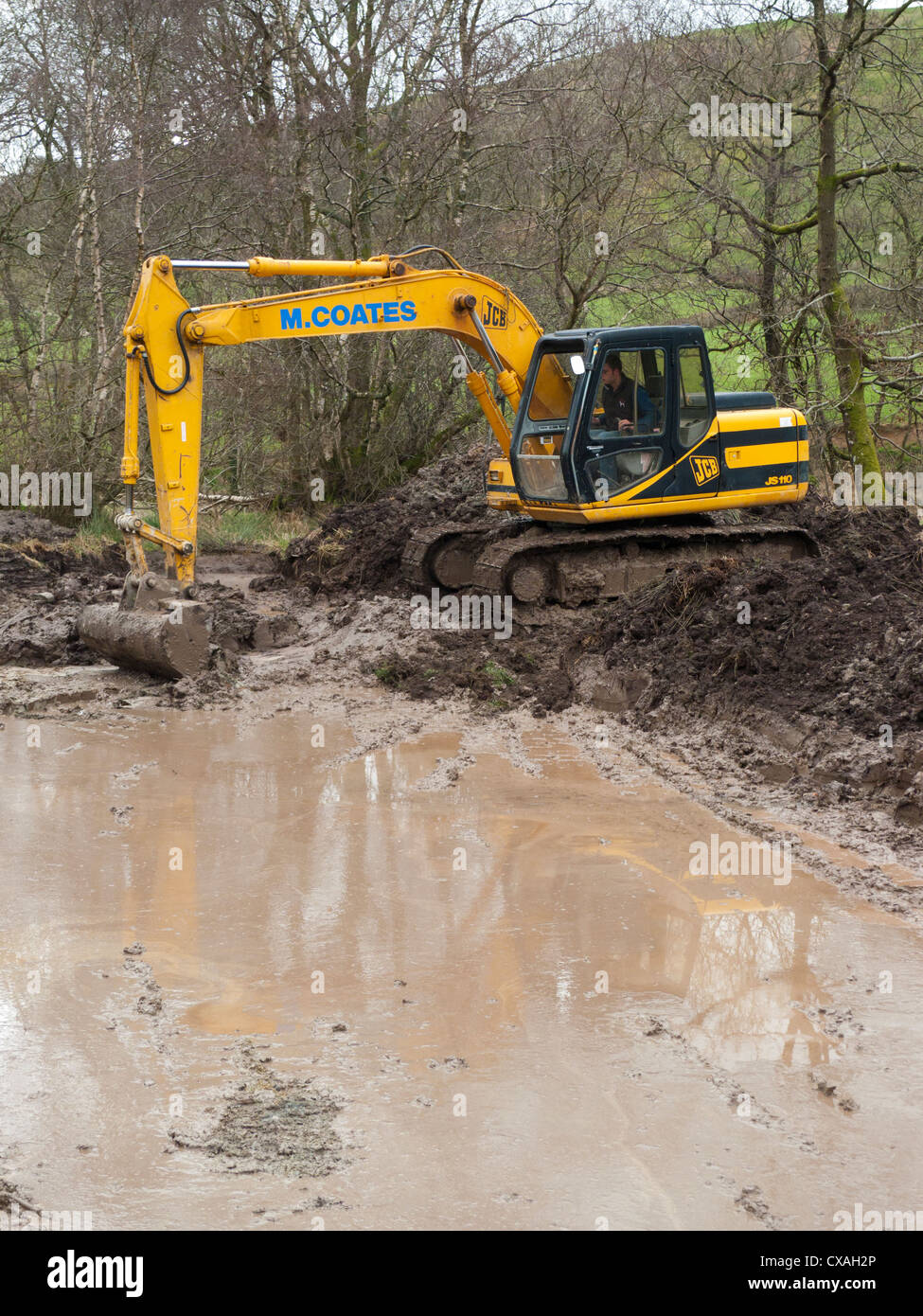 Contratista con una excavadora 360grados cavar un estanque de vida silvestre en una granja. Powys, Gales. Abril Foto de stock