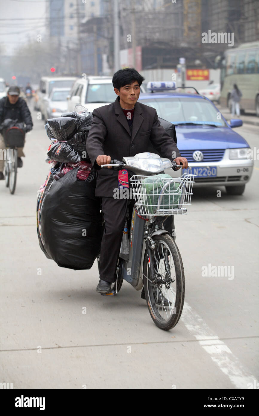 Shanghai, hombre conduce una bicicleta totalmente cargado Foto de stock