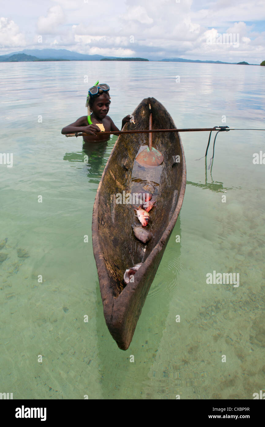Young Boy va a su canoa y pesca con arpón, laguna Marovo, Islas Salomón, el Pacífico Foto de stock