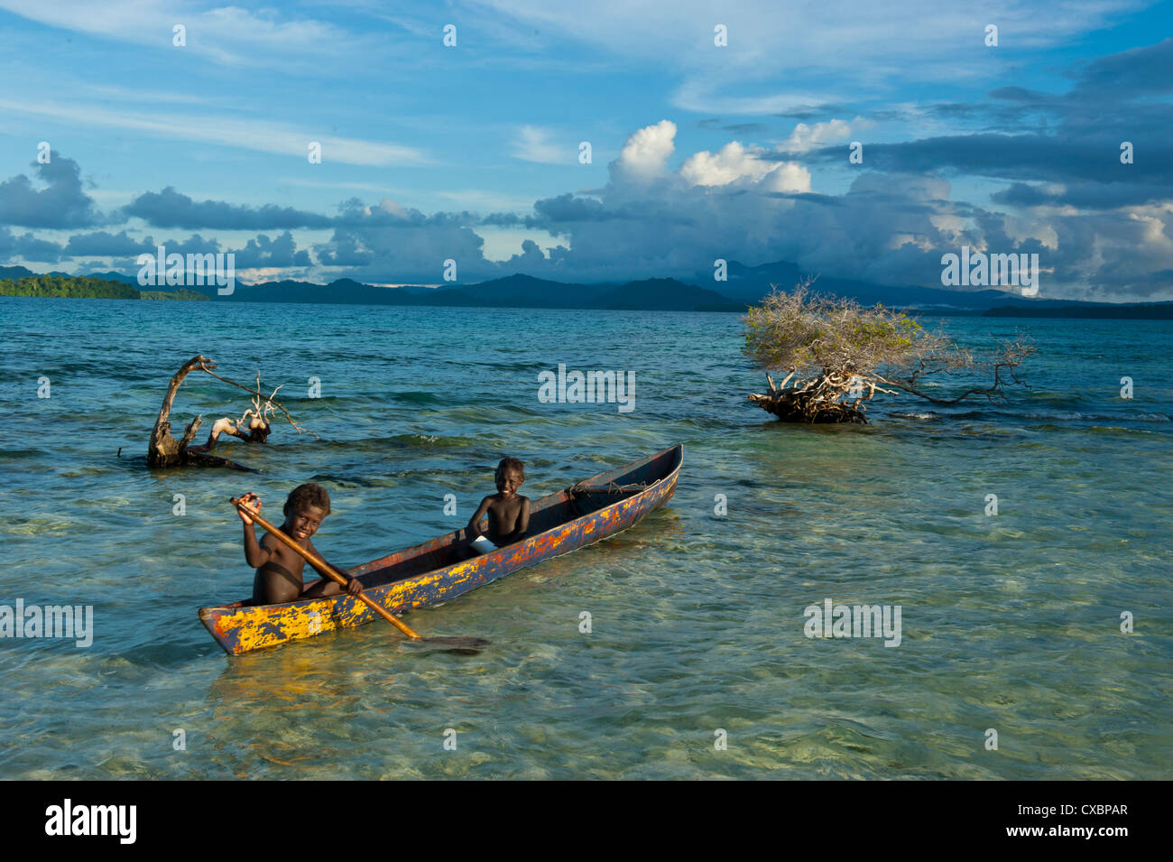 Los muchachos de pesca en la laguna de Marovo abajo nubes dramáticas, las Islas Salomón, el Pacífico Foto de stock