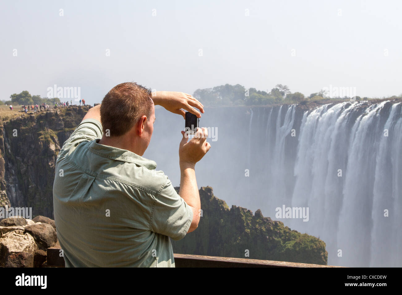 Un turista fotografías las Cataratas Victoria desde el lado de Zambia Foto de stock