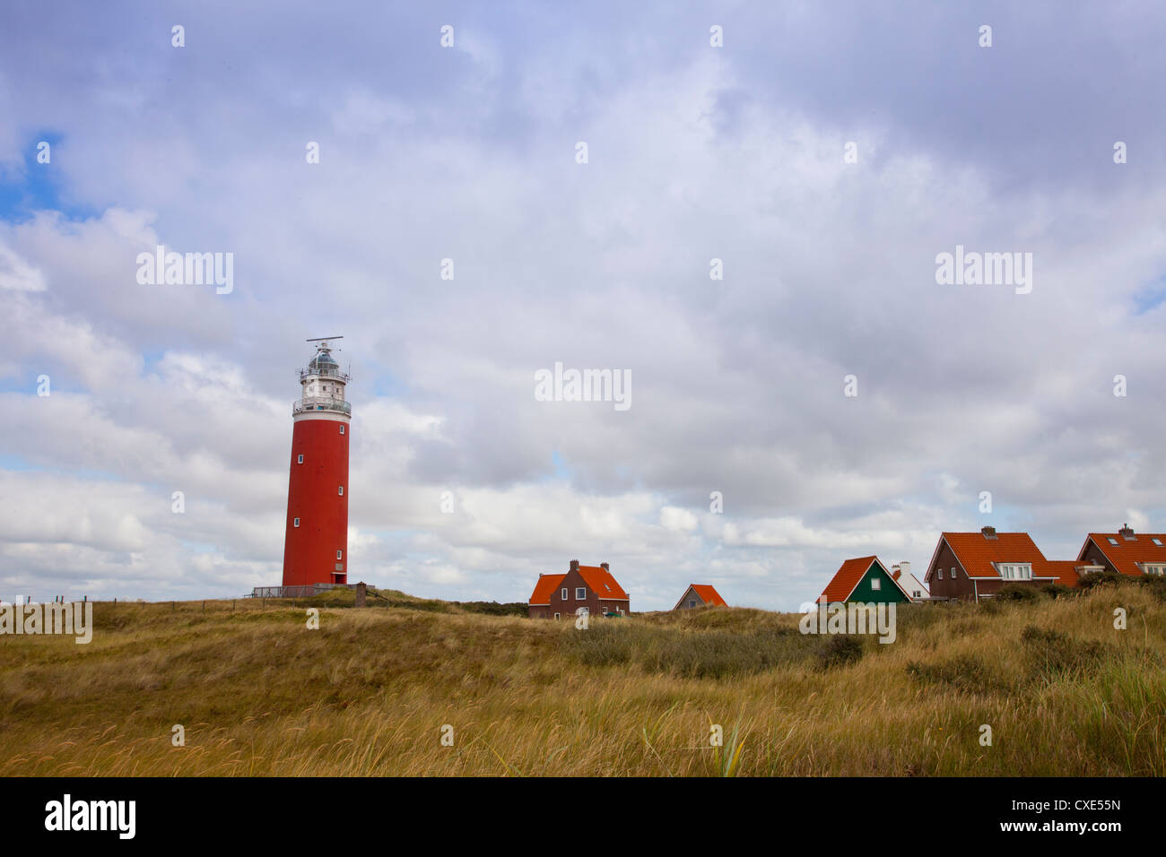 Faro rojo y casas en la isla de Texel, en los Países Bajos Foto de stock