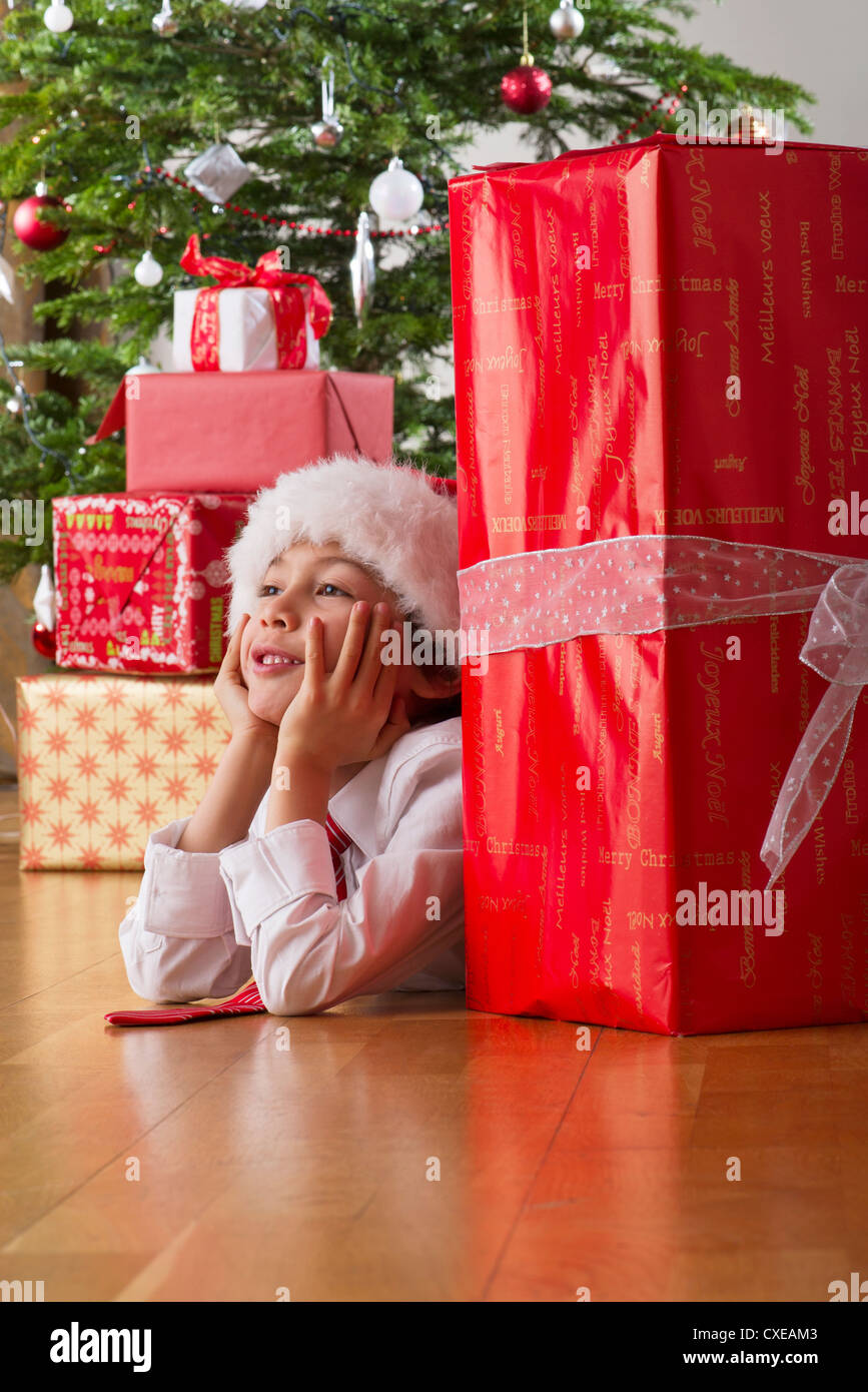 Niño acostado en el piso con los regalos de Navidad, soñar despierto  Fotografía de stock - Alamy