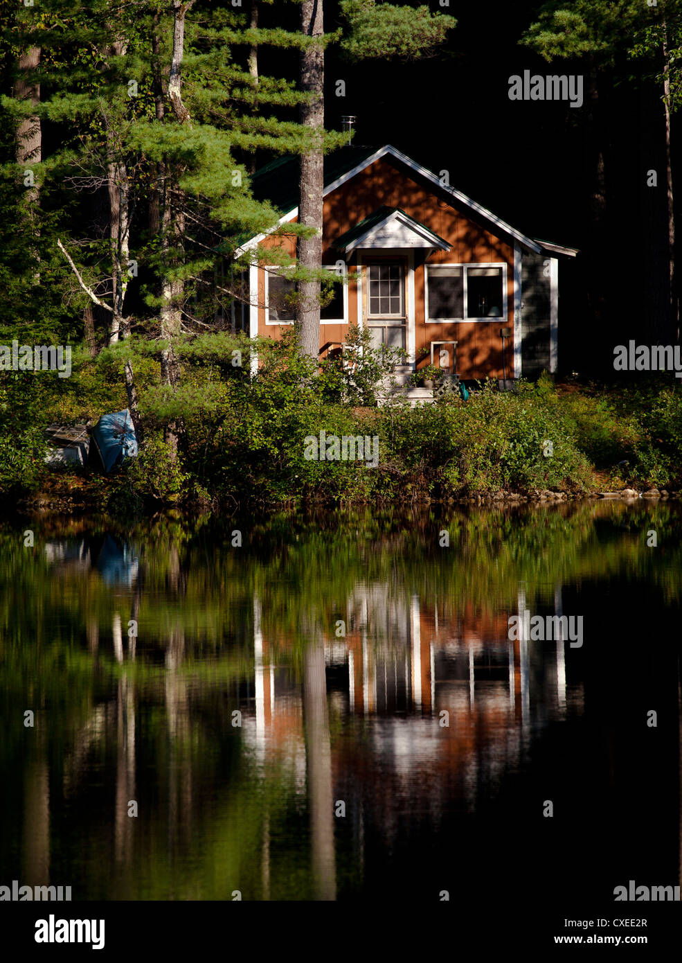 Cabaña en el bosque a la orilla de un lago. Canoas y reflexiones Fotografía  de stock - Alamy