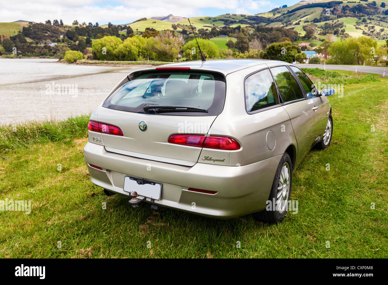 Color champán Alfa Romeo 156 Sportwagon, aparcado al lado de puerto de Akaroa en Nueva Zelandia. Foto de stock