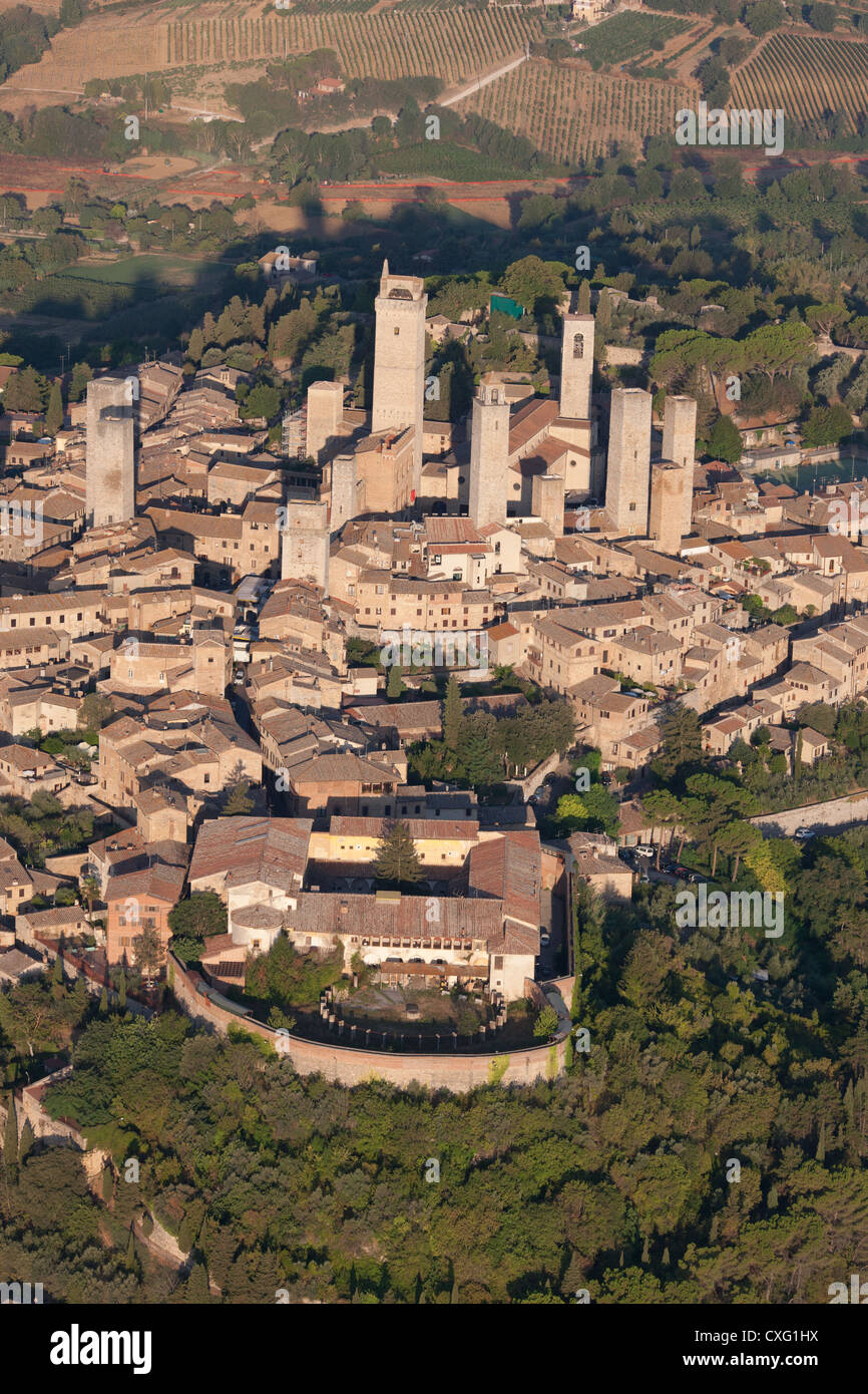 VISTA AÉREA. Ciudad medieval en la cima de una colina con sus numerosas torres construidas por ricas familias hace siglos. San Gimignano, Provincia de Siena, Toscana, Italia. Foto de stock