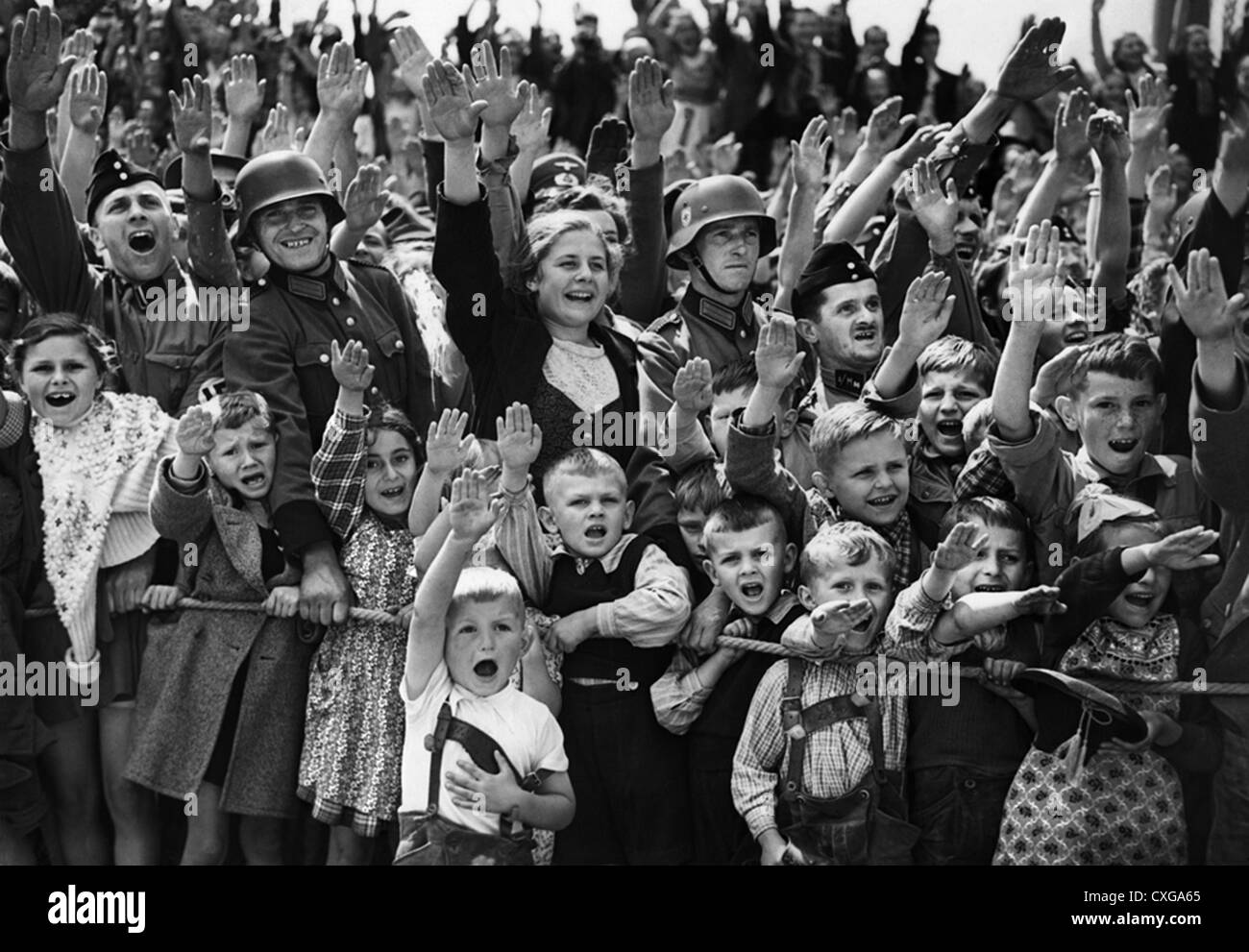Los niños alemanes y soldados dar el saludo nazi durante el desfile Foto de stock