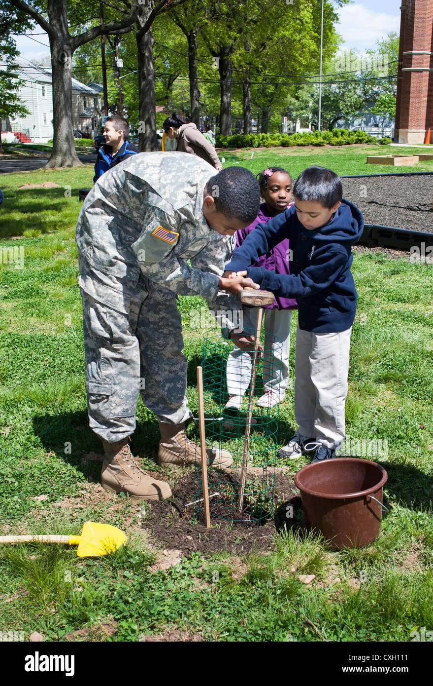 ROTC voluntario ayudando a los niños de la escuela de plantar un árbol en Arbor Day Foto de stock