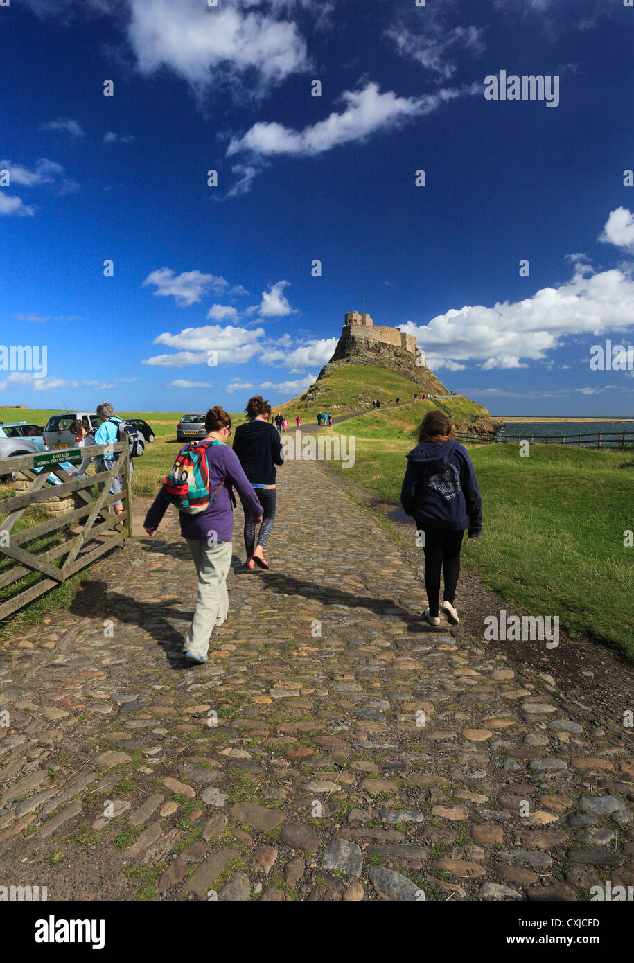 Los visitantes caminando hacia el castillo de Lindisfarne, Holy Island. Foto de stock
