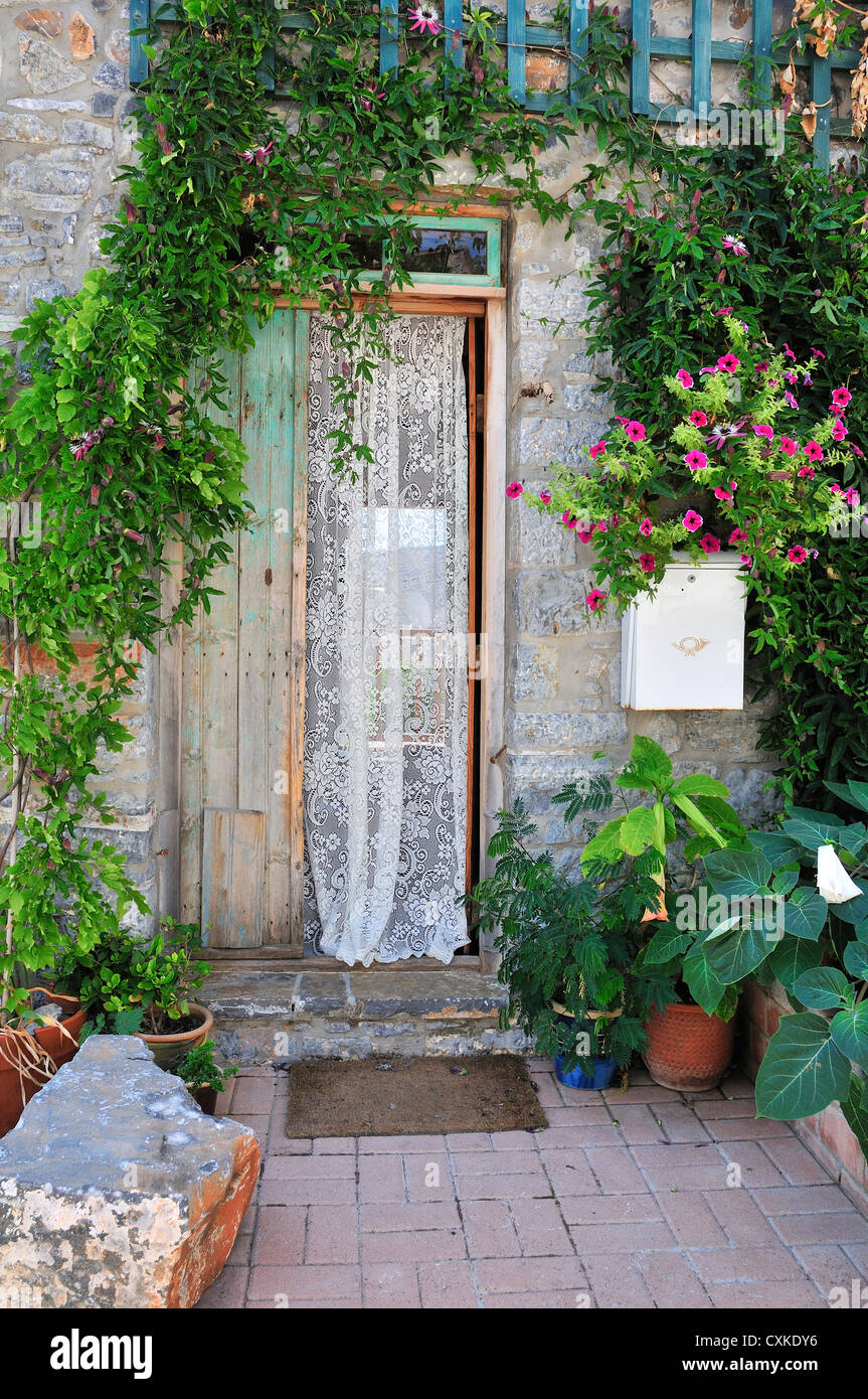 Puerta griega con cortina de encaje,rodeado de plantas en la colina village de Pano Elounda, Creta, Grecia Foto de stock