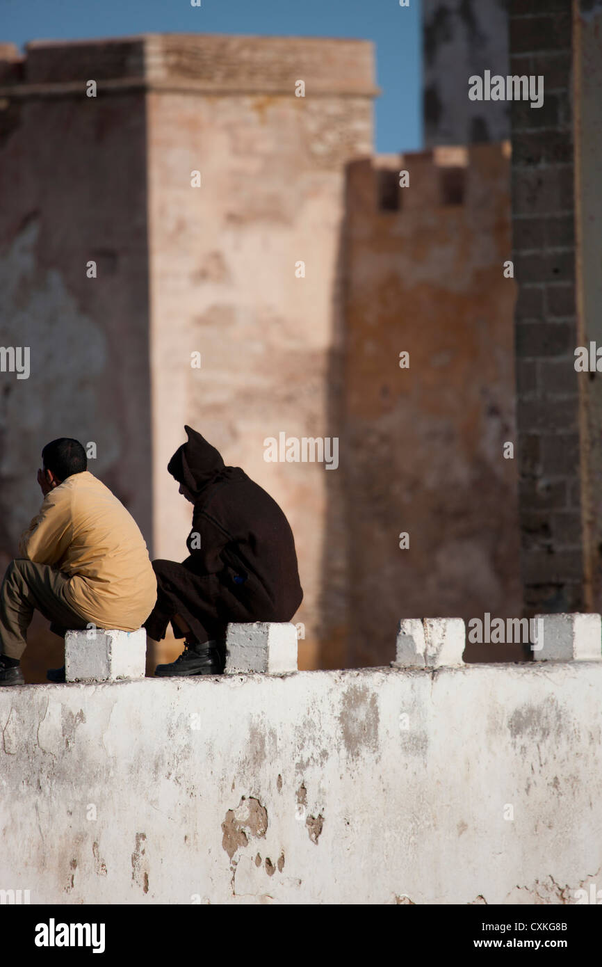 Dos hombres sentados en el muro de la ciudad, Essaouira, Marruecos Foto de stock