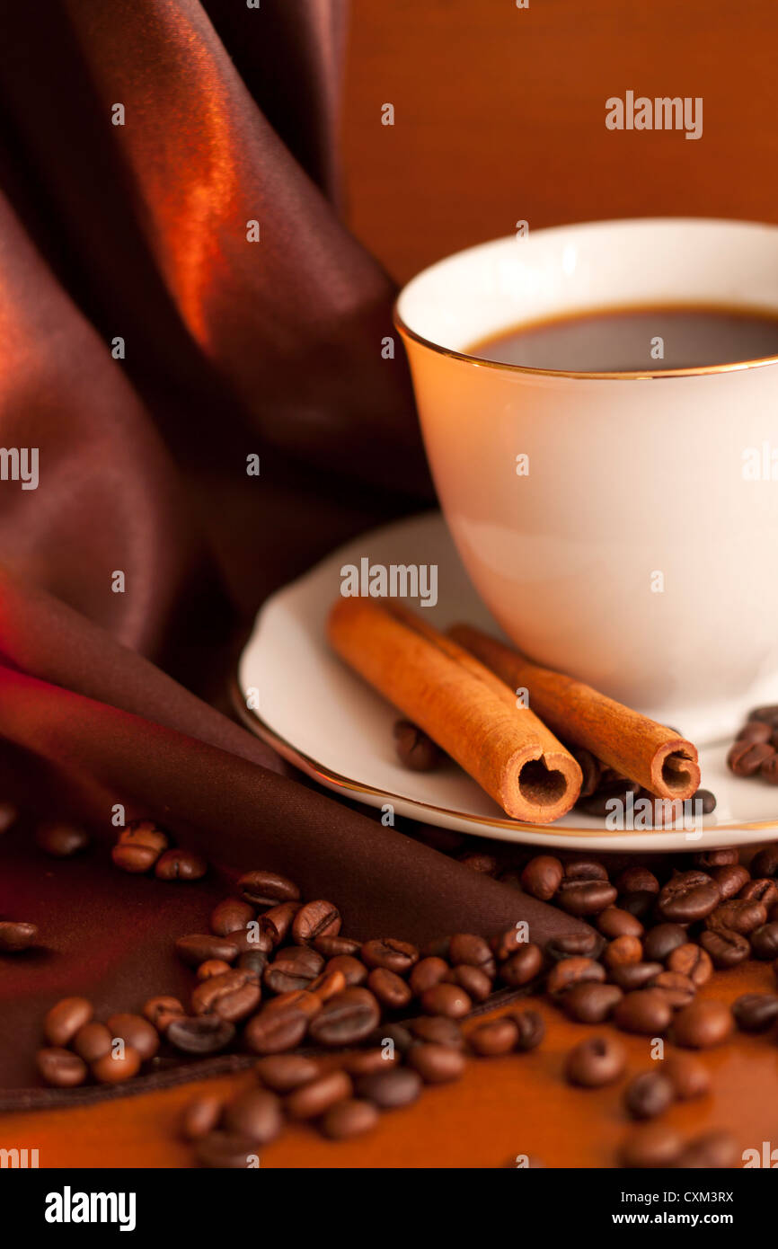 Taza de café tostado en grano y palitos de canela en la mesa de madera