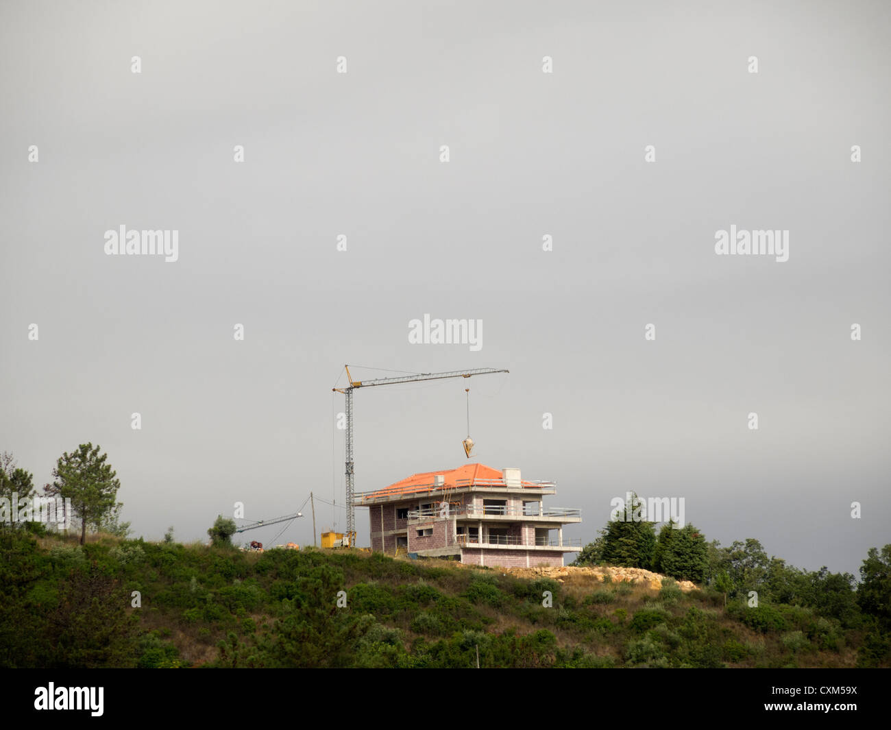 Grúa de construcción sobre una compilación sitio contra un cielo gris oscuro Foto de stock