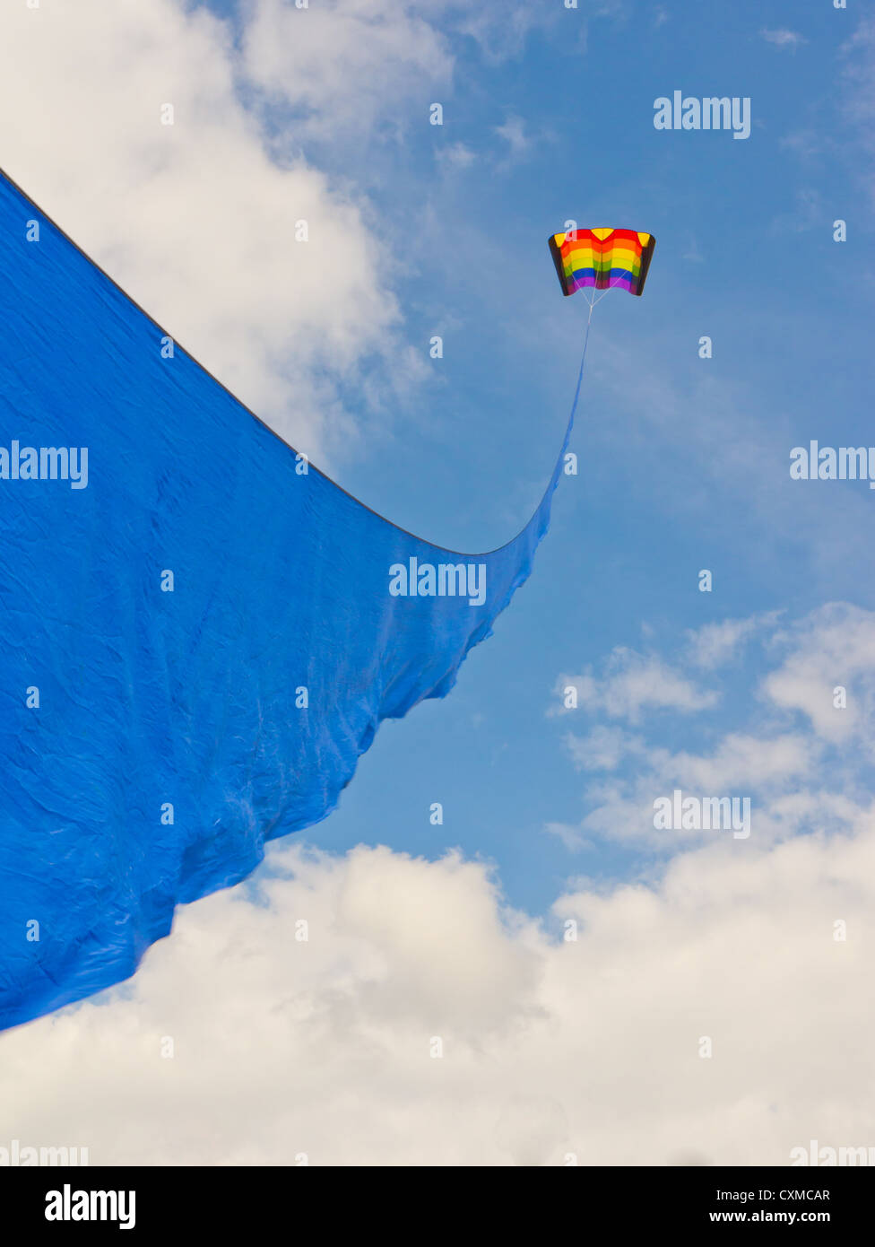 Un arco iris de colores kite vuela al final de una cinta azul Foto de stock