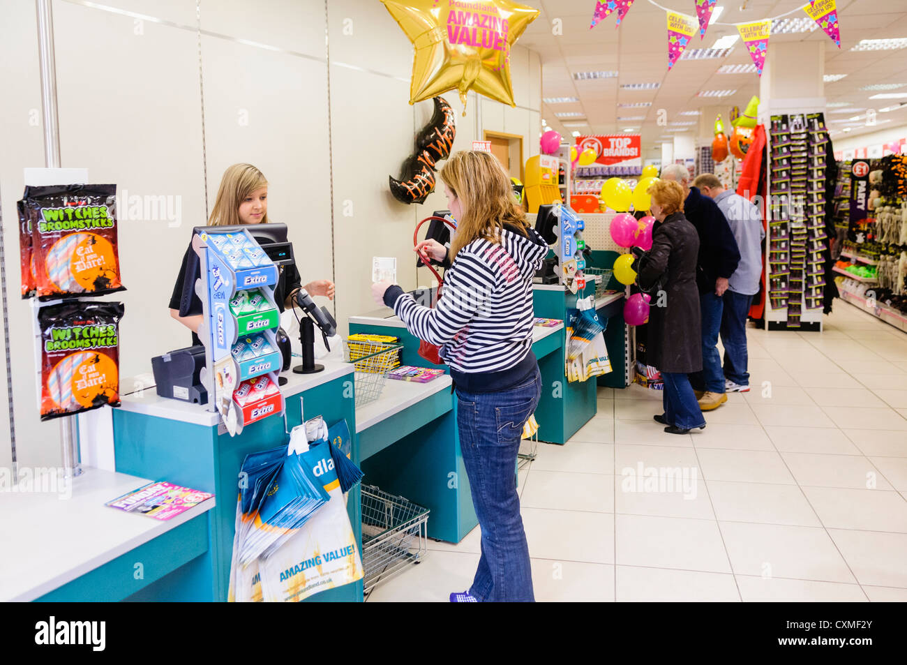 Los clientes se sirven en el Poundland hasta en una tienda. Foto de stock