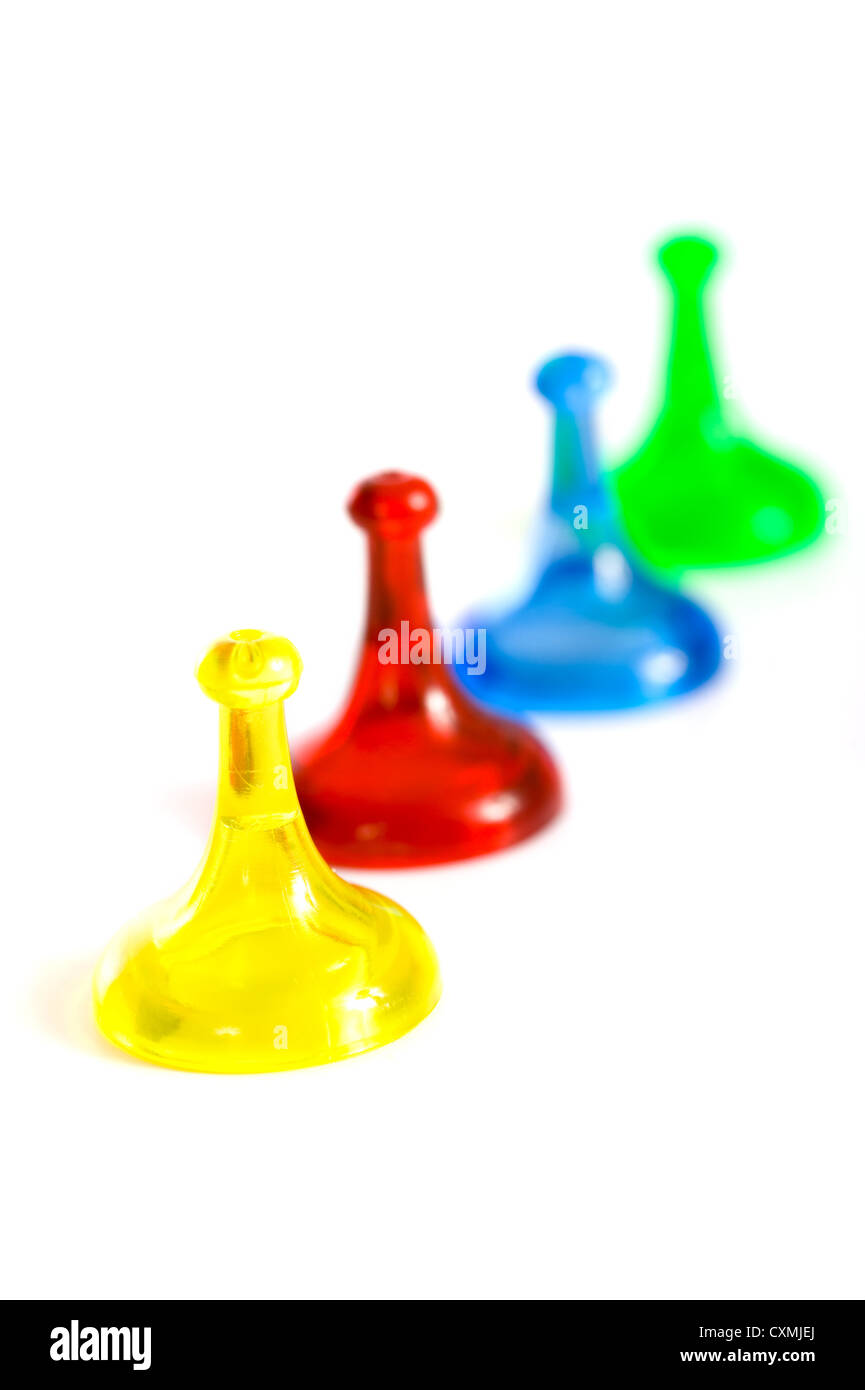 Una fila de coloridas piezas de juego genérico sobre un fondo blanco, el foco está en la pieza de juego amarillo en primer plano Foto de stock