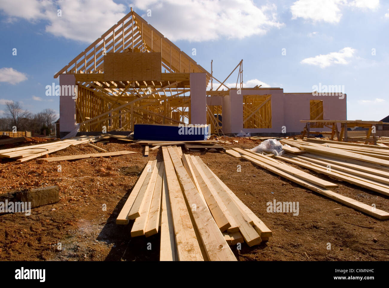 Casa nueva en construcción con madera, vigas y suministros Foto de stock