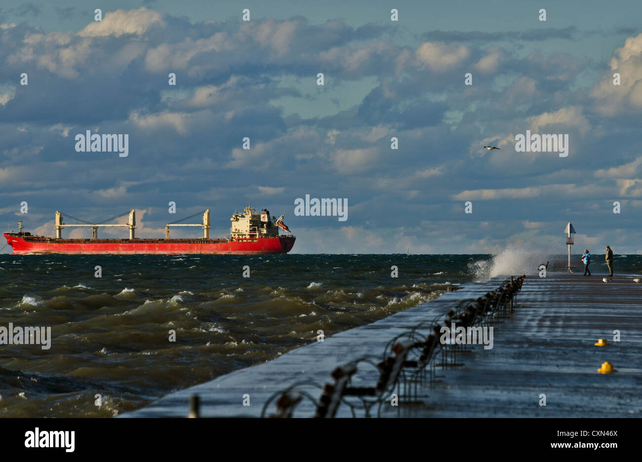 Dos personas paseo por el muelle de Puerto Dalhousie, en un día muy entrecortado en el Lago Ontario, el barco está anclado Orsula detrás Foto de stock