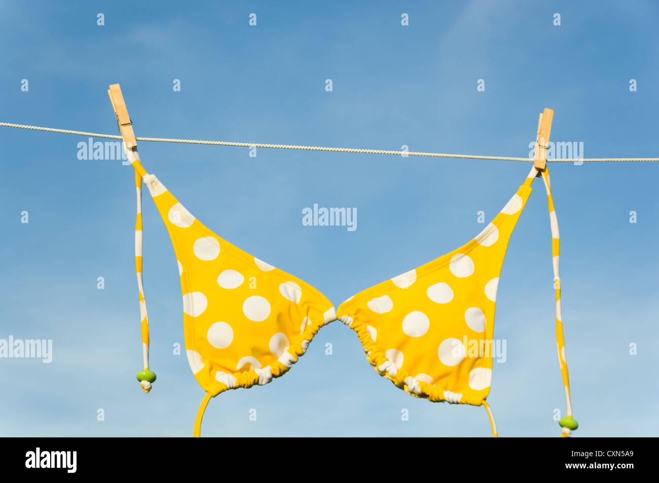 Una de Itsy Bitsy teeny weeny yellow polka dot bikini colgando de un tendedero con espacio de copia Foto de stock