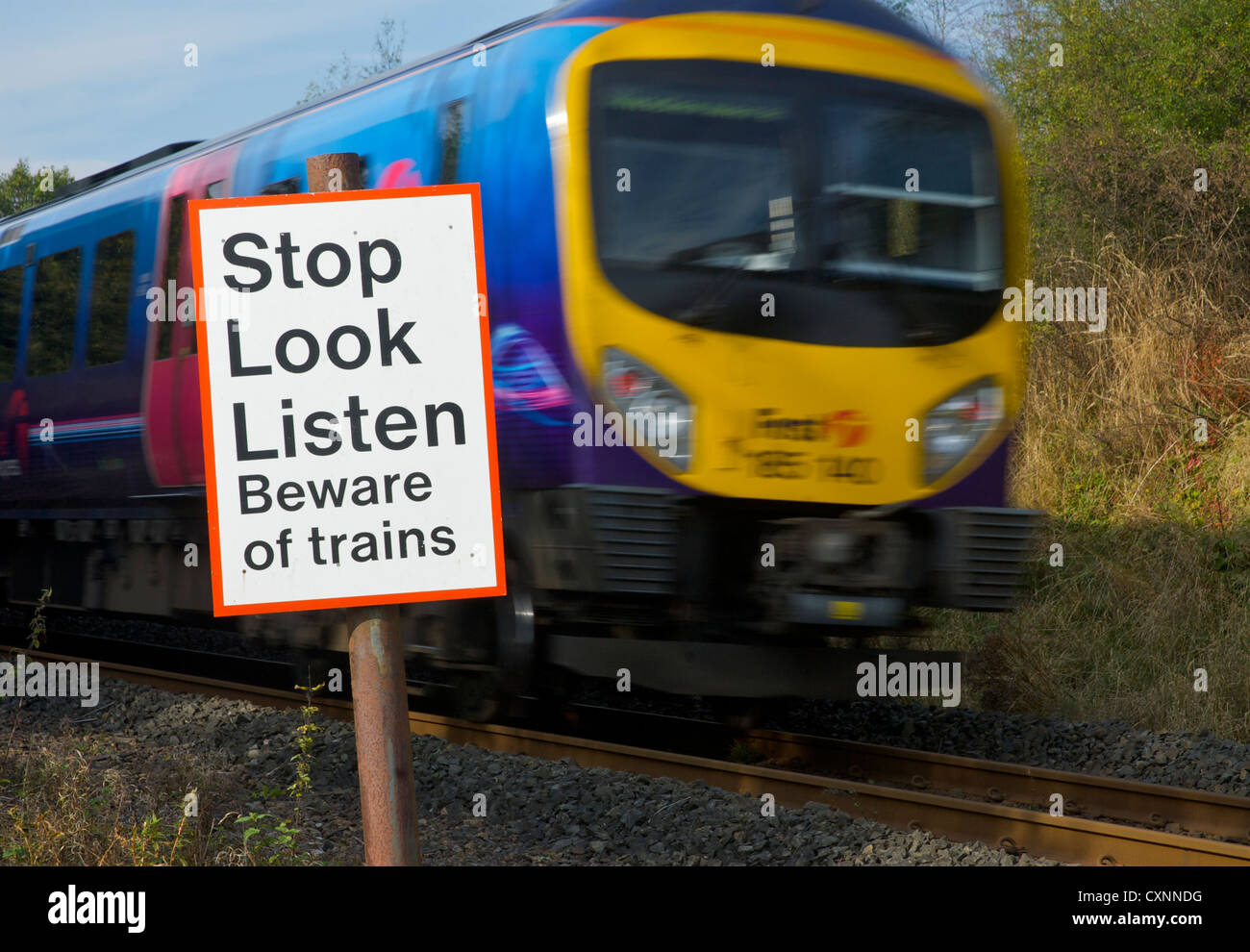 Tren a toda velocidad y firmar, por cruce de peatones a lo largo de la línea de ferrocarril, para advertir a la gente sobre trenes Foto de stock