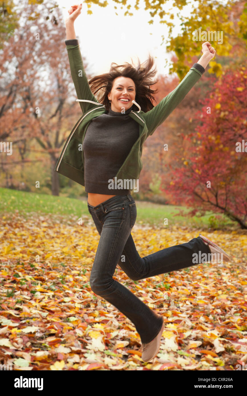 Mujer saltando en hojas de otoño Foto de stock