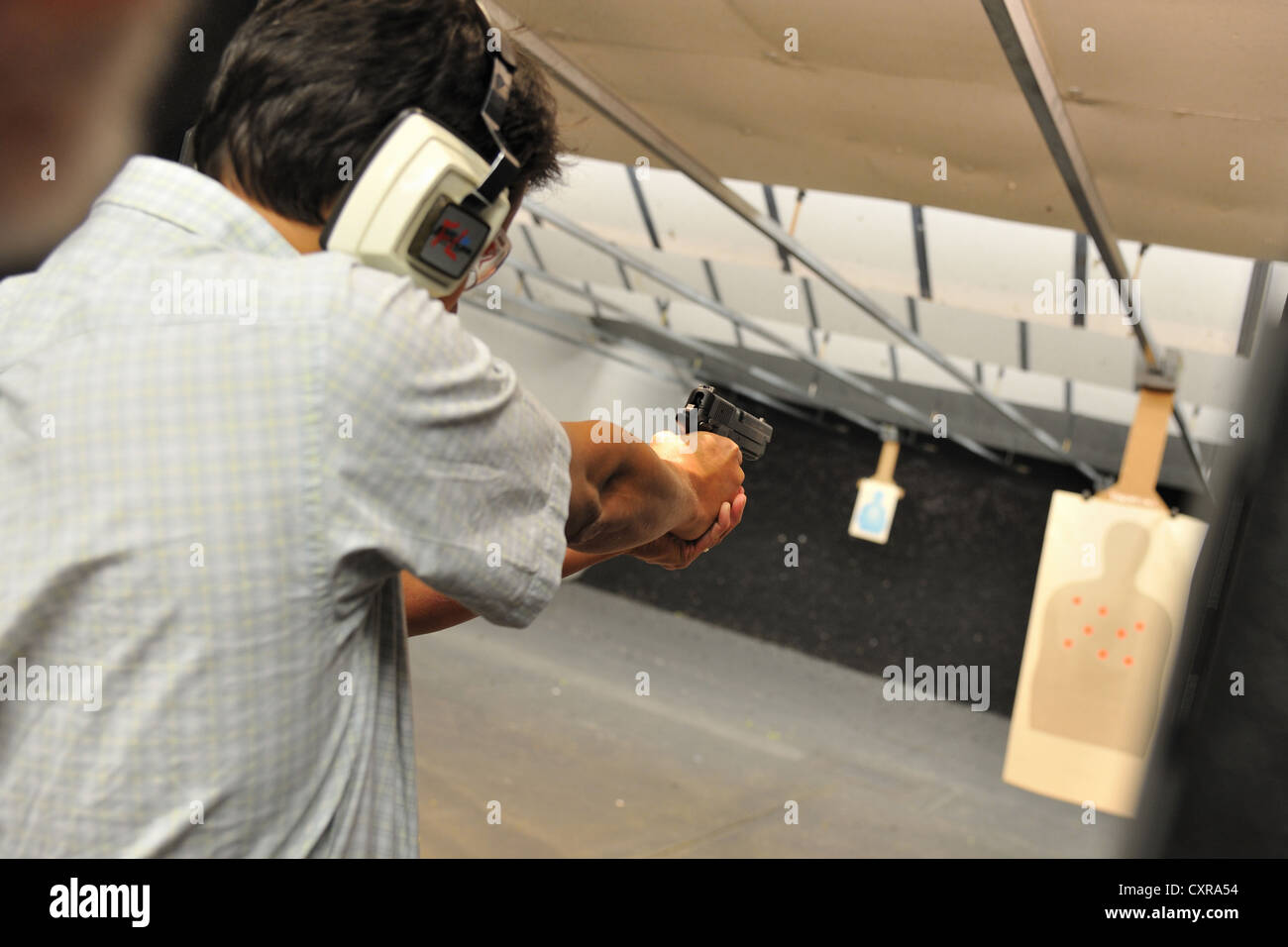 Shooter macho apuntando pistola durante la práctica de focalización en el polígono de tiro, Colorado, EE.UU. Foto de stock