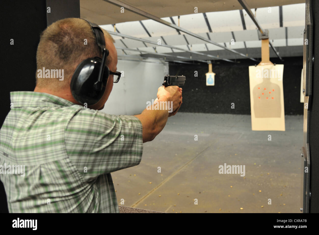 Shooter macho apuntando pistola durante la práctica de focalización en el polígono de tiro, Colorado, EE.UU. Foto de stock