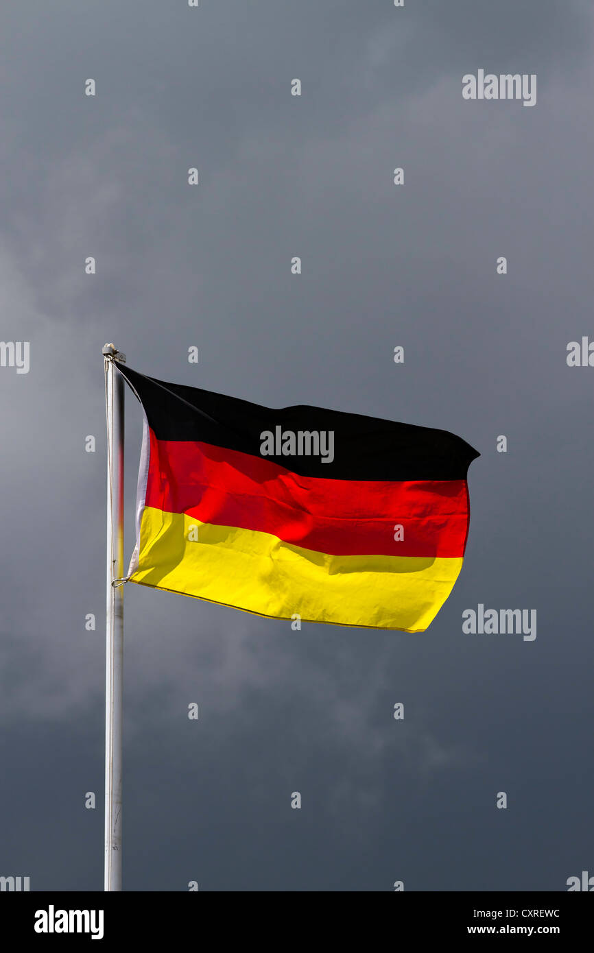 La bandera nacional alemana, nubes oscuras en la espalda, imagen simbólica Foto de stock