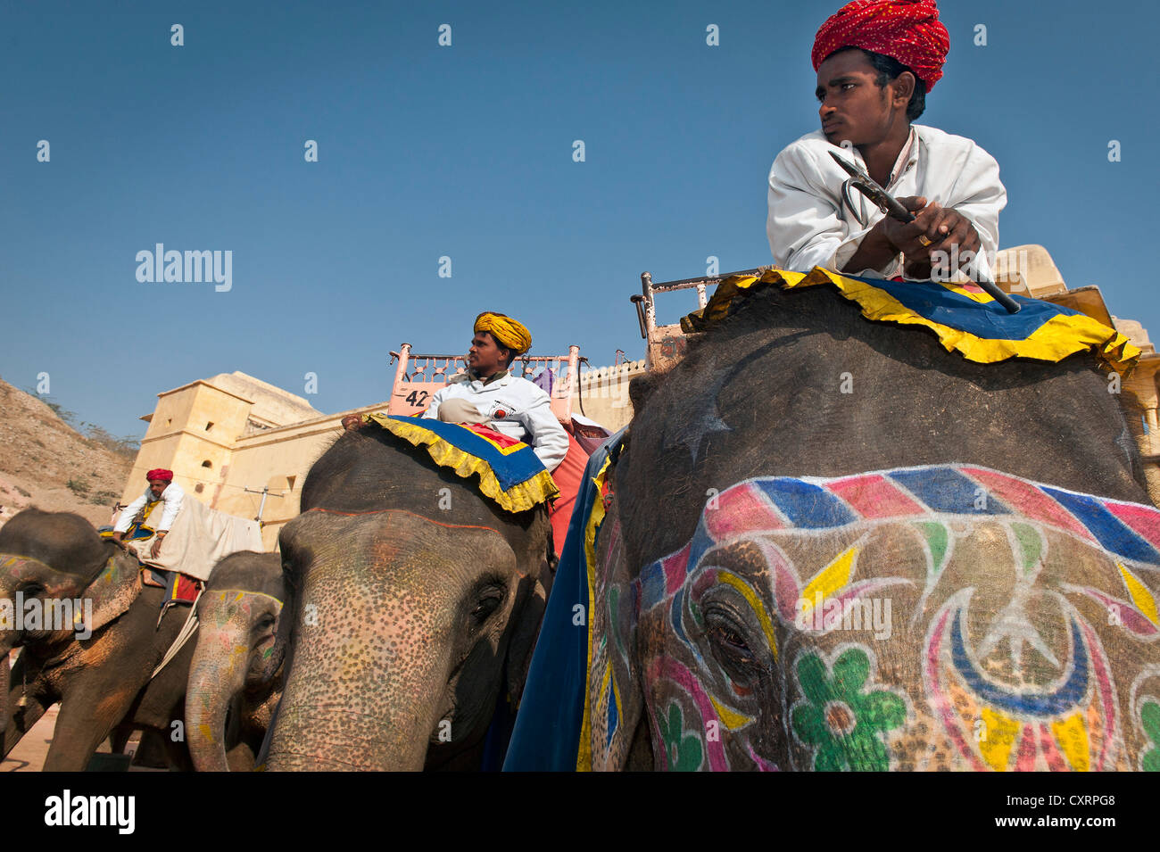 Mahout o conductor de elefantes con un turbante rojo sentada sobre un elefante pintado, Fuerte Amer, ámbar o ámbar Fort Palace, Jaipur. Foto de stock