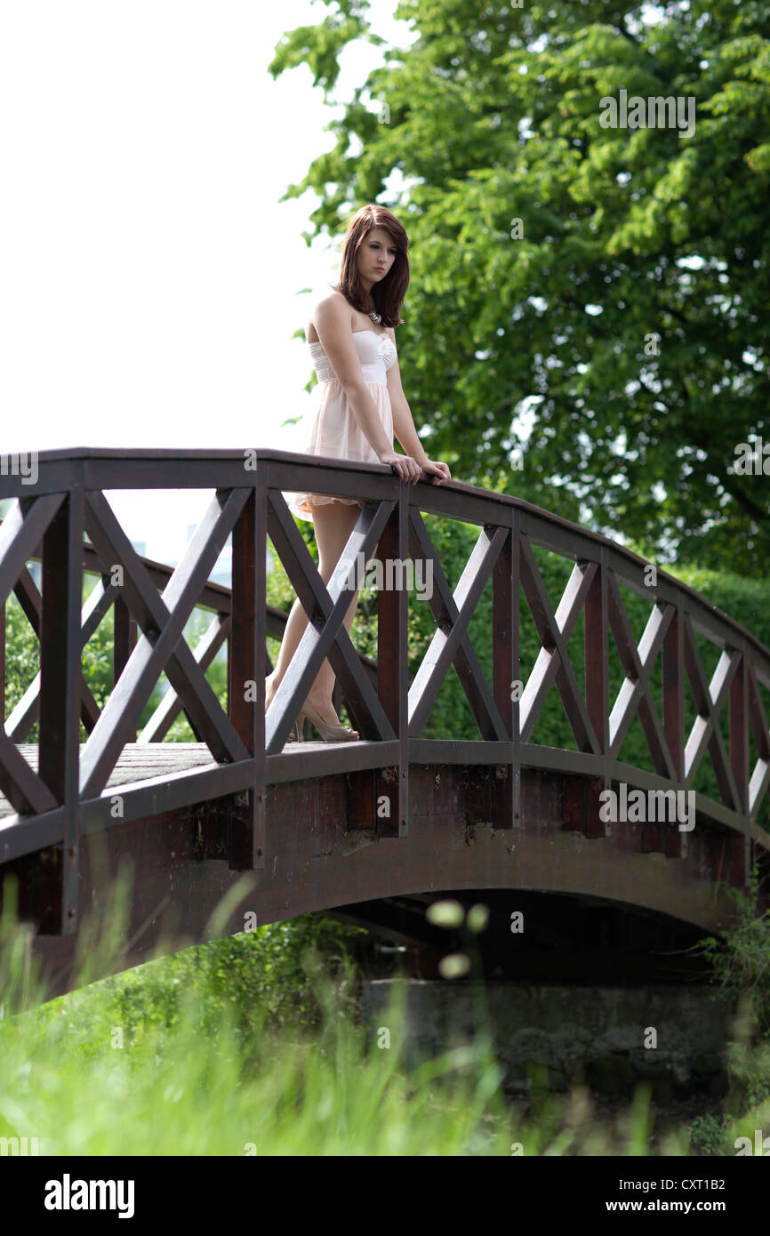 Mujer joven llevaba un vestido corto de color beige y los zapatos de tacón  alto de pie sobre un puente de madera Fotografía de stock - Alamy