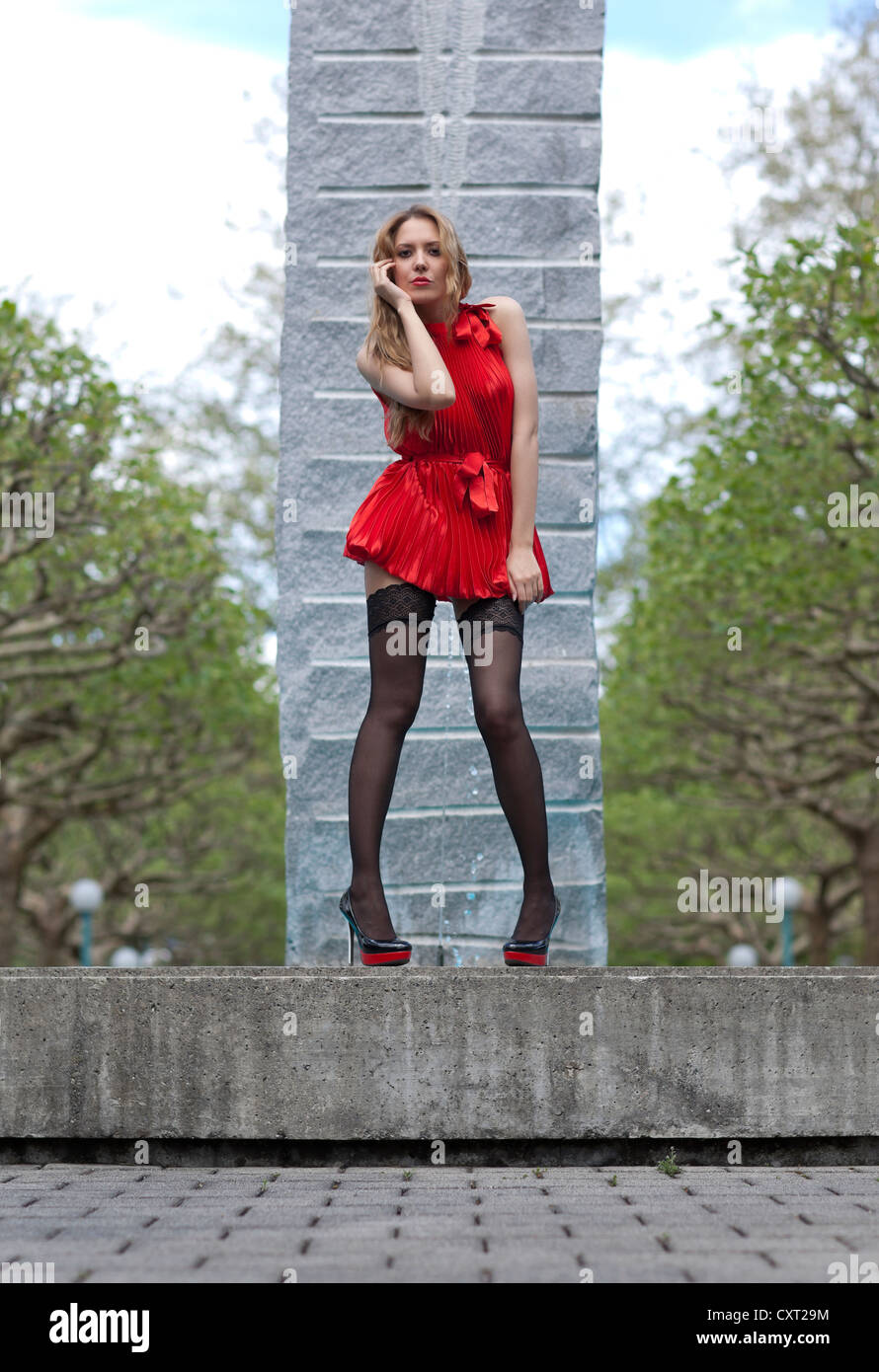 Joven en vestido corto rojo, y tacones altos posando en fuente Fotografía de stock - Alamy