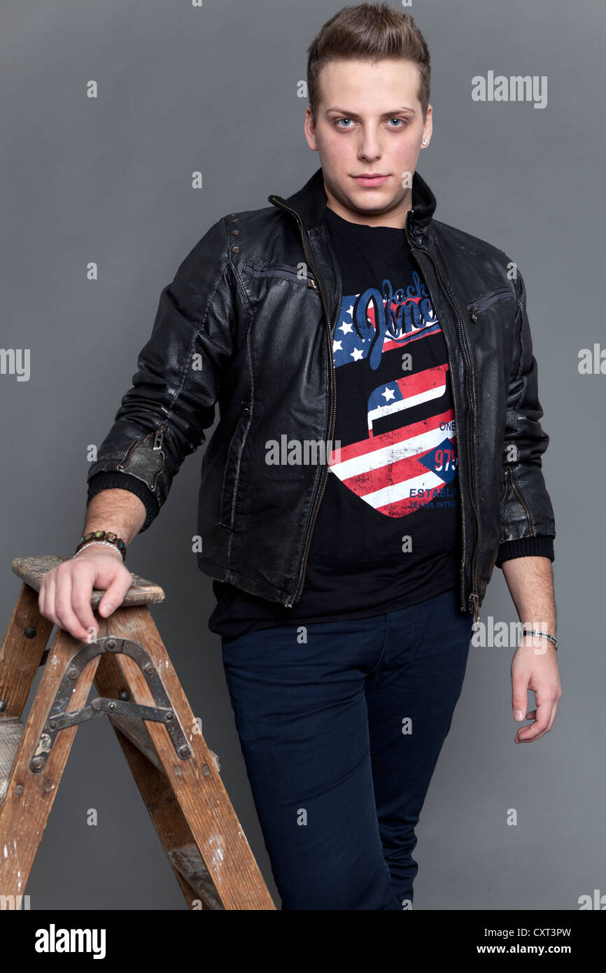 Joven llevaba una chaqueta de cuero y jeans, apoyada contra una antigua  escalera de madera Fotografía de stock - Alamy