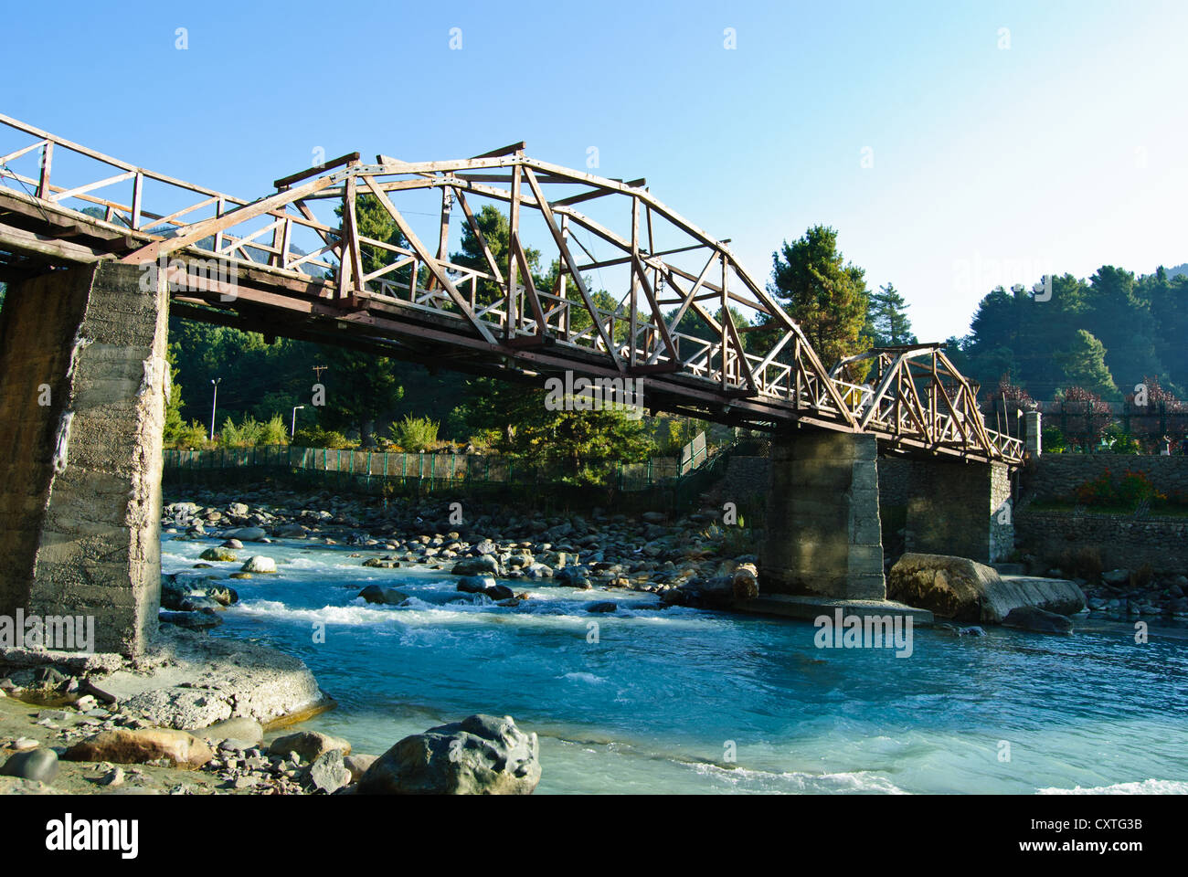 Un puente de madera sobre pilotes de pilares de piedra, cruzando el río Lidder en Pahalgam Foto de stock