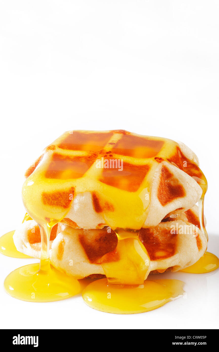 Waffles con miel sobre blanco Foto de stock