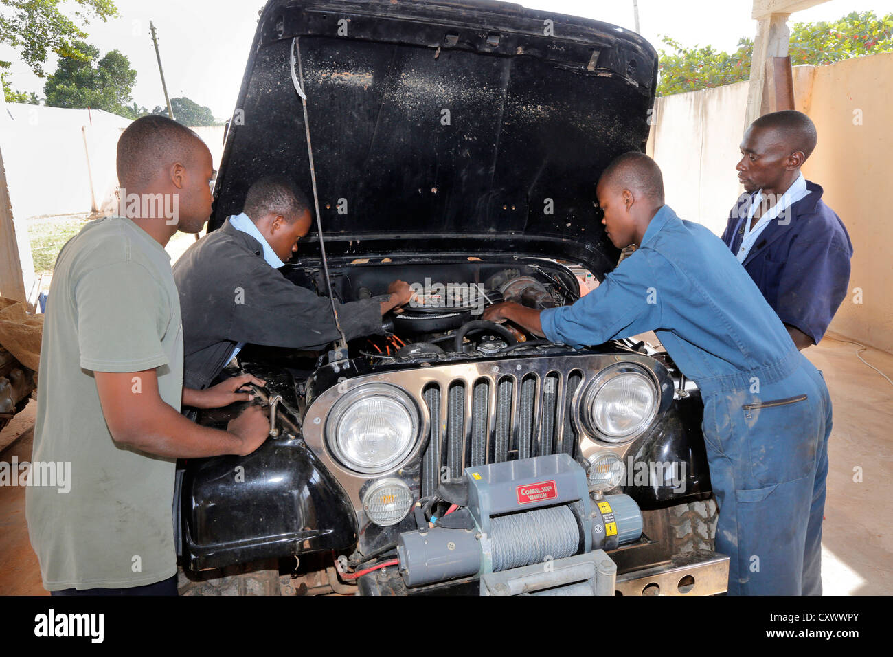 Mecánica de jóvenes trabaja en un motor de automóvil. Machui Centro Vocacional Machui, Zanzíbar, Tanzania Foto de stock