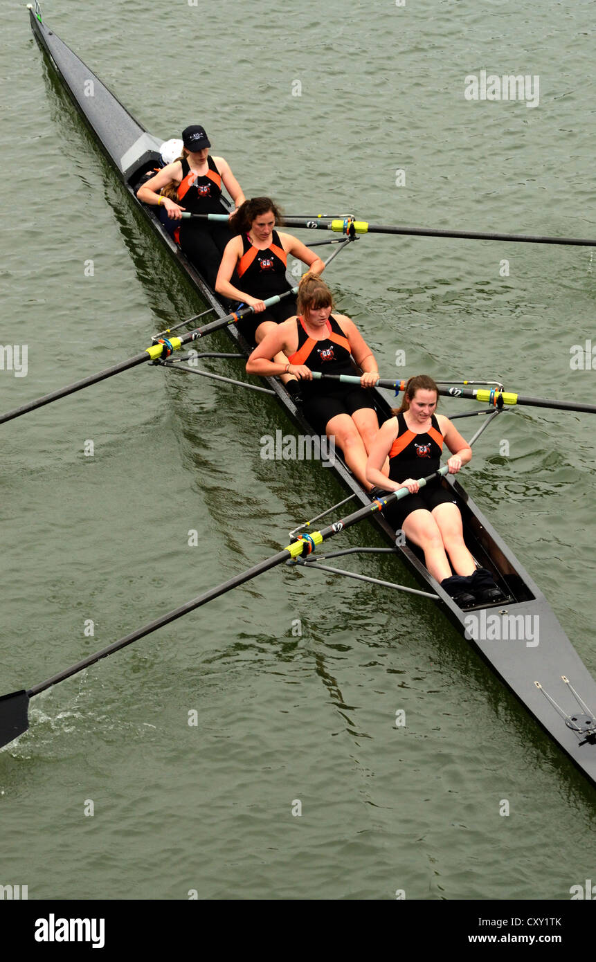 Cuatro mujeres en el barco remando sculling team competir en carrera universitaria Foto de stock